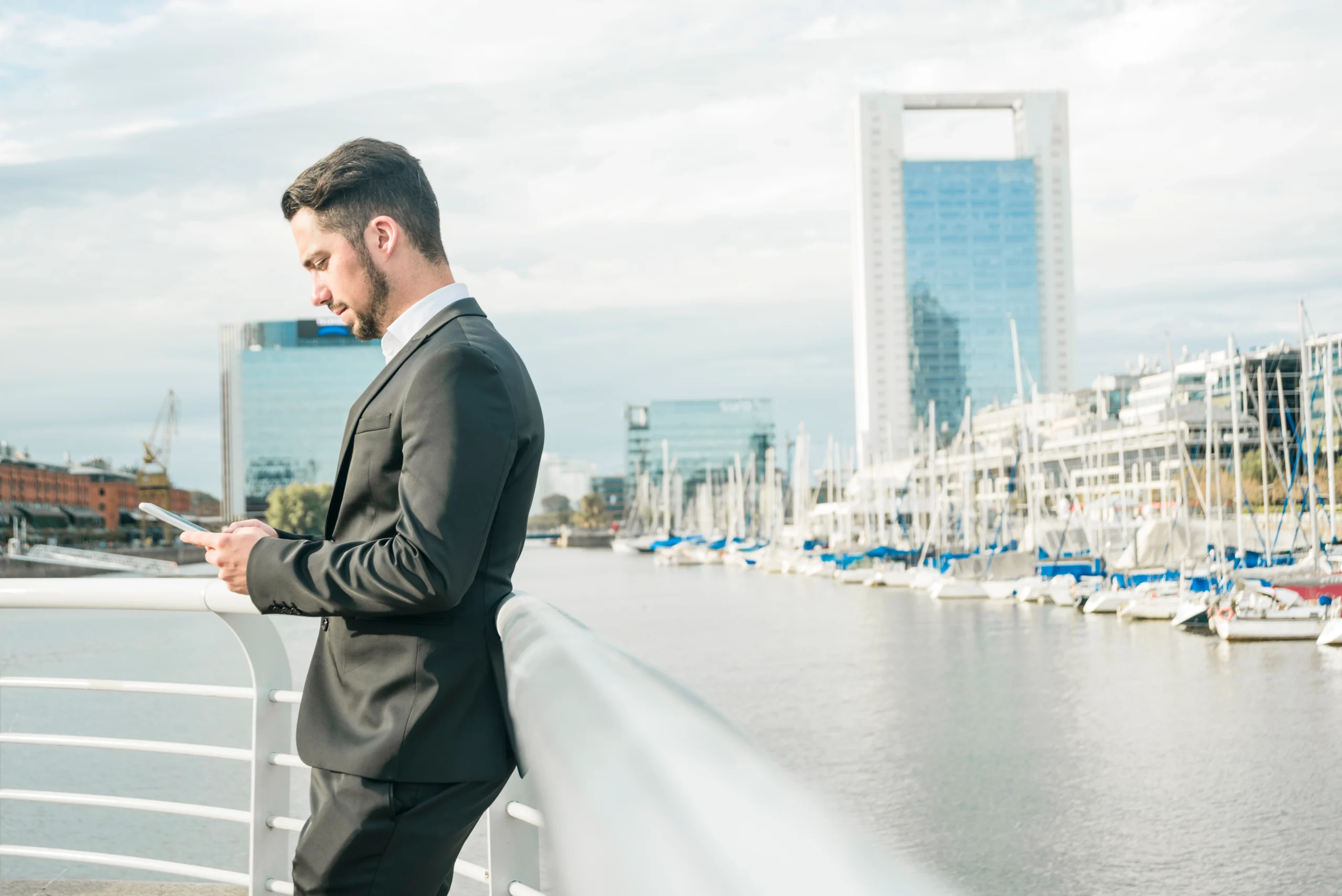 young-businessman-standing-near-railing-using-mobile-phone